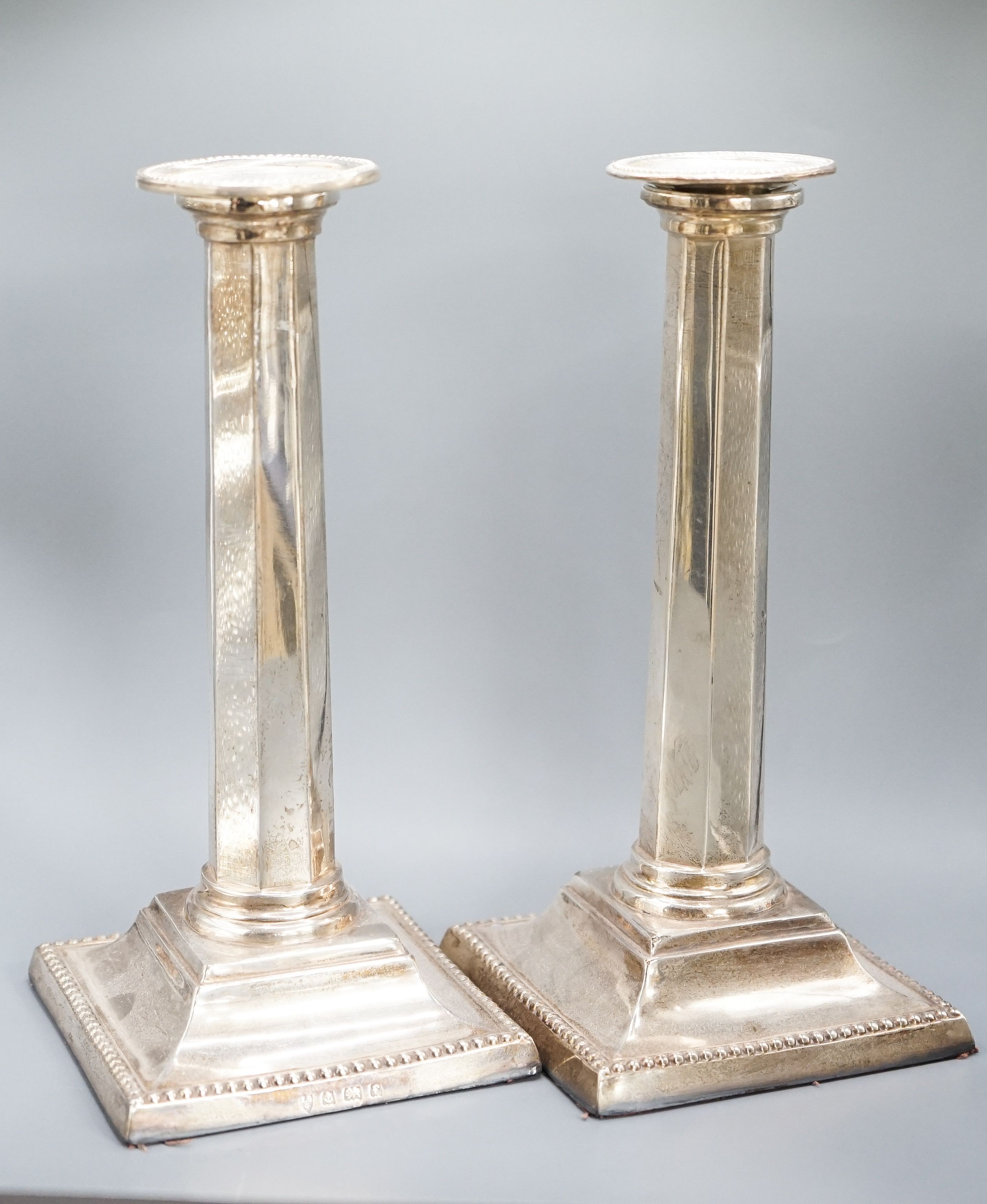 A pair of Edwardian silver candlesticks, with panelled columns, Birmingham, 1905, 20.8cm, weighted.